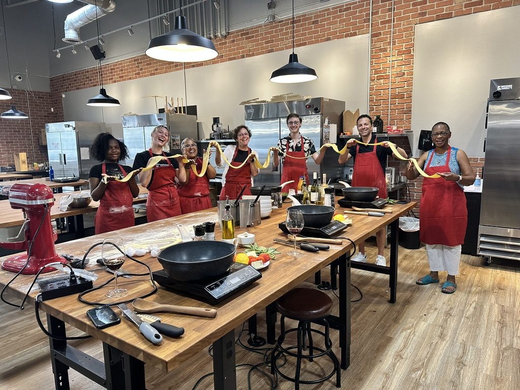 A team holding the fresh pasta they made together at The Local Epicurean in East Lansing.